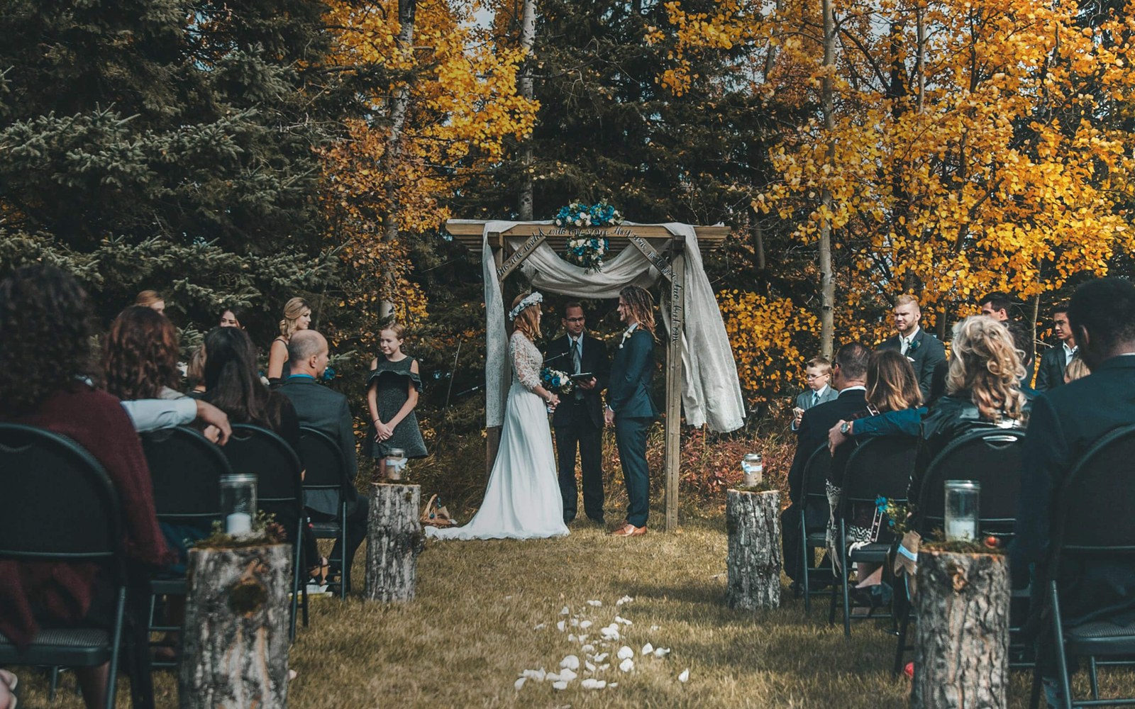 Laulību ceremonija mežā ar viesiem, kas sēž abās ejas pusēs